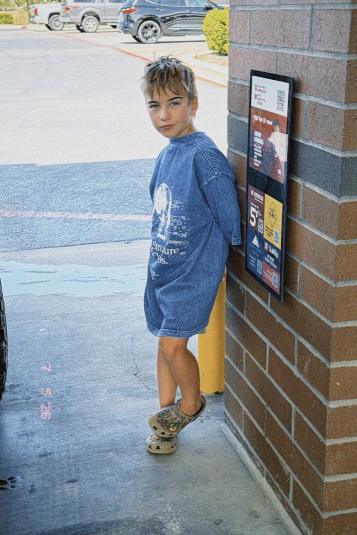 Joseph, the kid founder of Texas Toy Lab, leaning against a brick wall