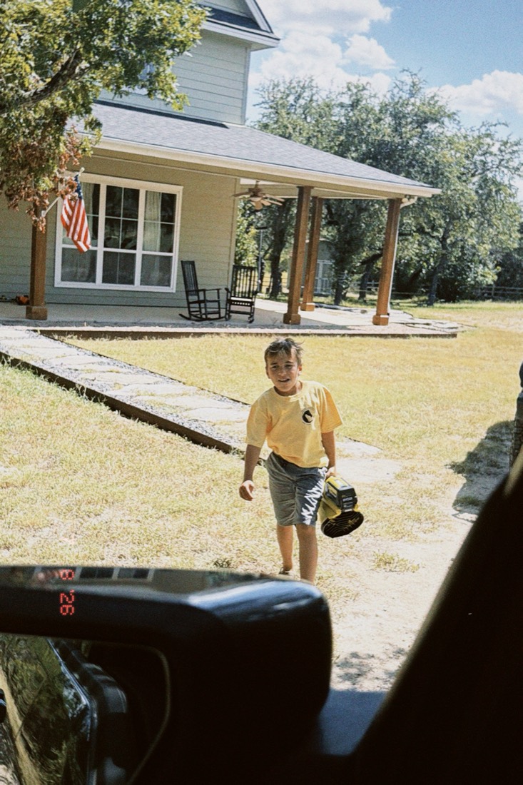 Joseph carrying a leaf blower across the yard