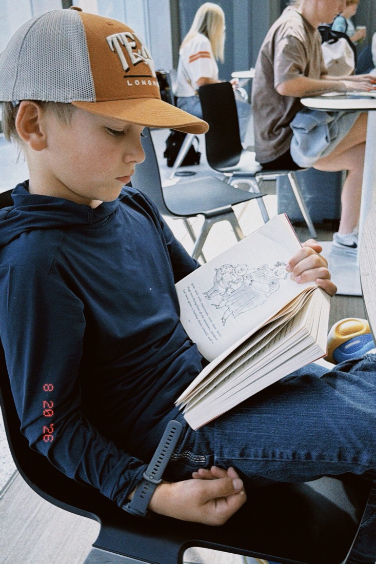 Joseph in a Texas cap reading a book