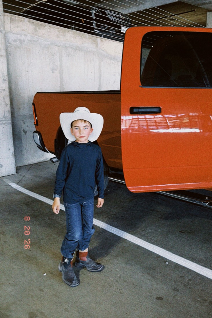 Joseph in a white cowboy hat in front of an orange pickup truck