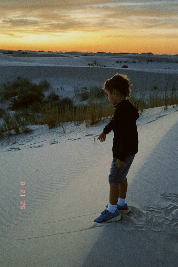 Joseph walking on white sand dunes at sunset
