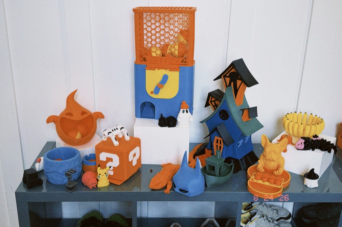 A shelf crowded with colorful 3D printed toys from the Texas Toy Lab workshop